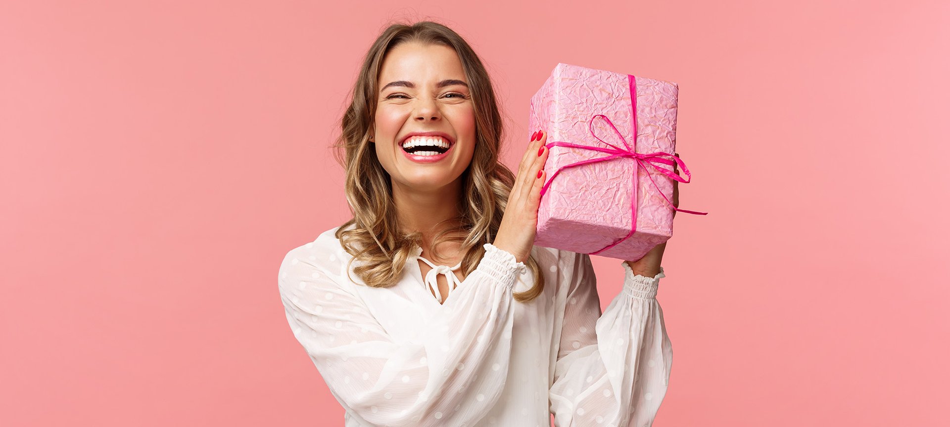 uśmiechnięta kobieta trzymająca w ręce prezent