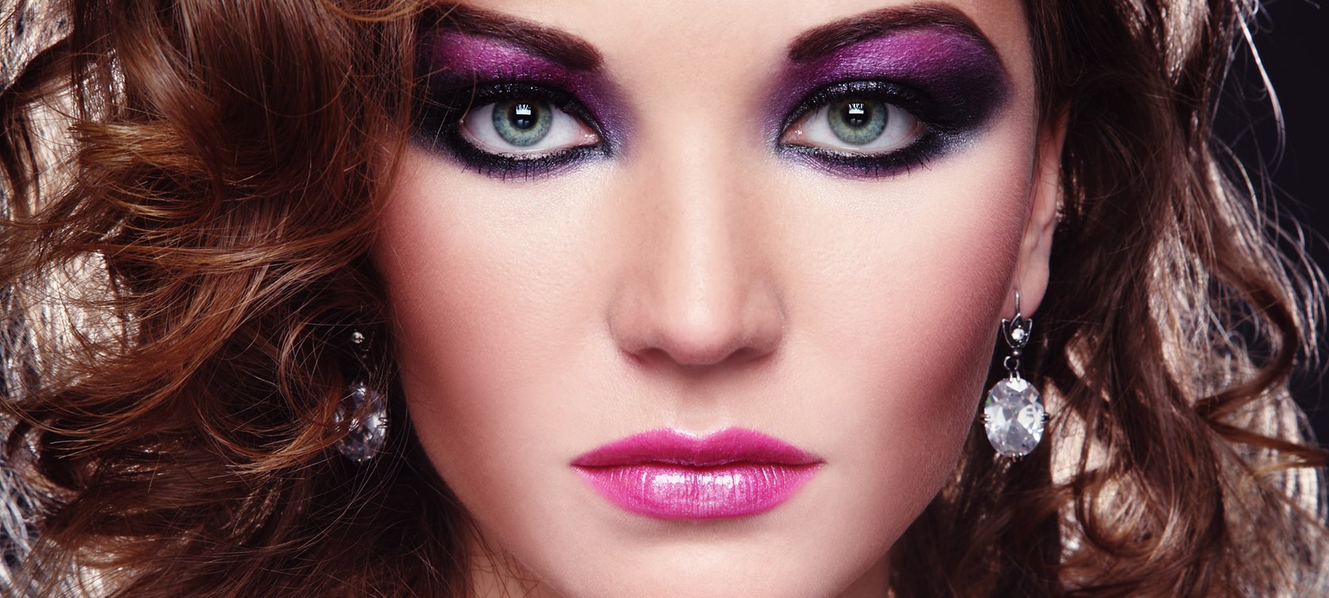 Portret kobiecy z wyrazistym, w odcieniach różu i fioletu makijażem w stylu lat 80.