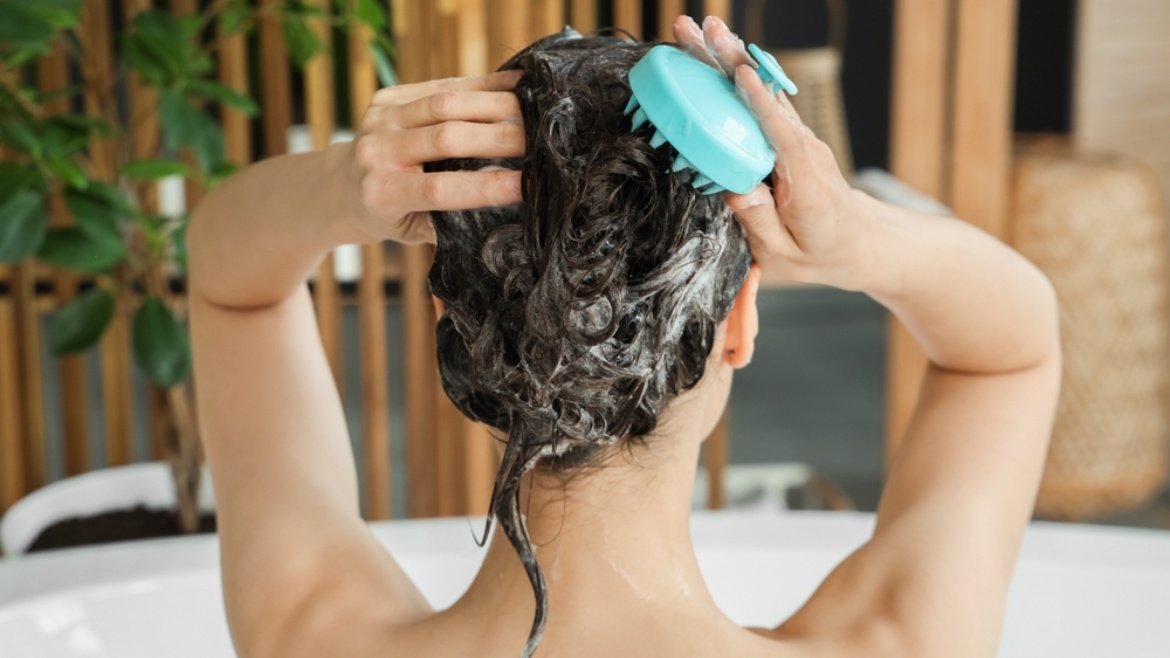 Kobieta nakładająca peeling na skórę głowy specjalną szczotką