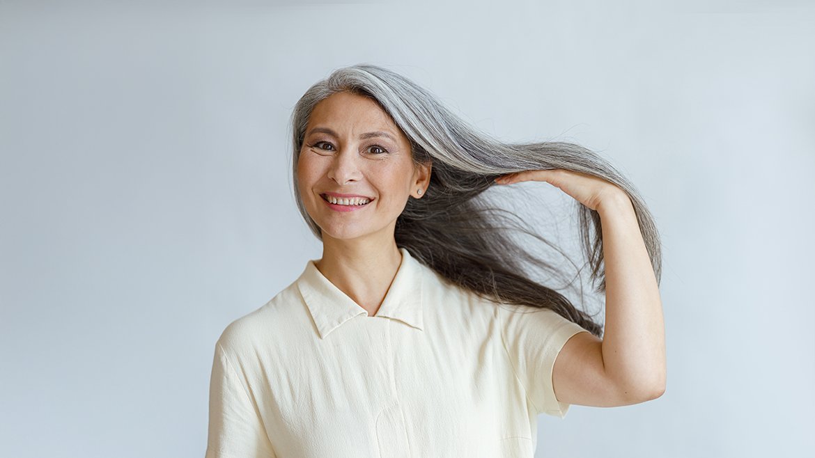 Kobieta o azjatyckiej urodzie z siwymi refleksami na włosach.