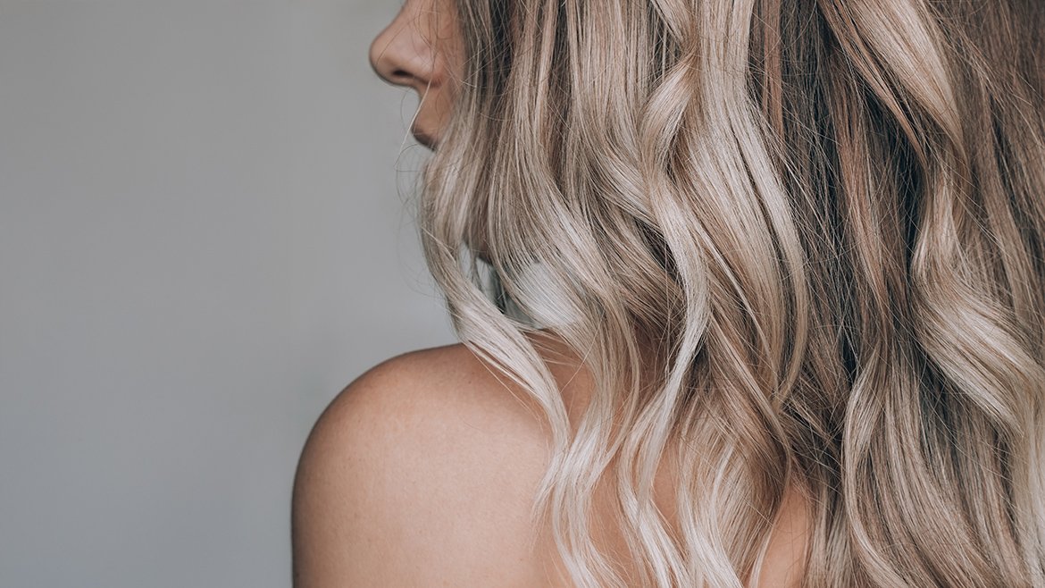 Kobieta z falowanymi, długimi włosami w odcieniu chłodnego blondu