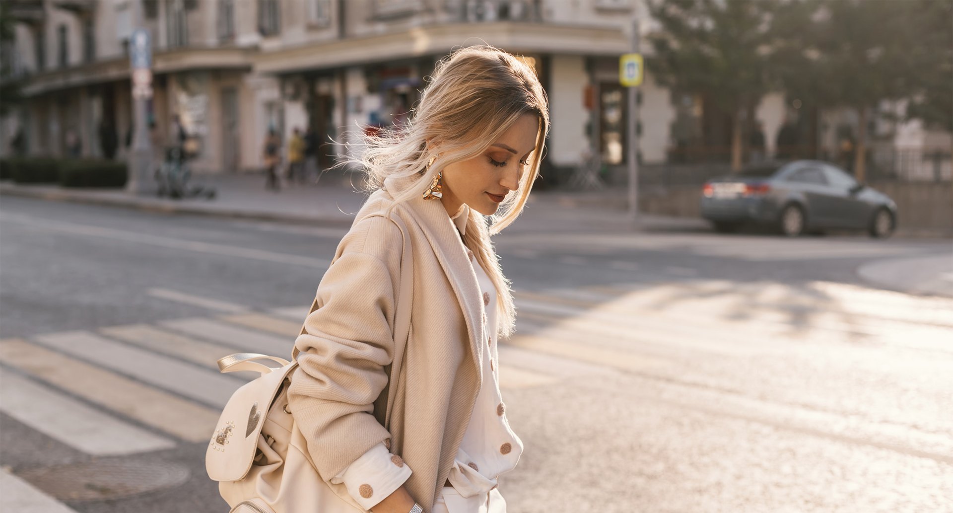 Kobieta w ciepłym odcieniu blond spaceruje po mieście 