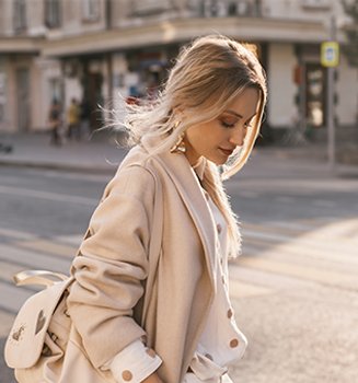 Kobieta w ciepłym odcieniu blond spaceruje po mieście
