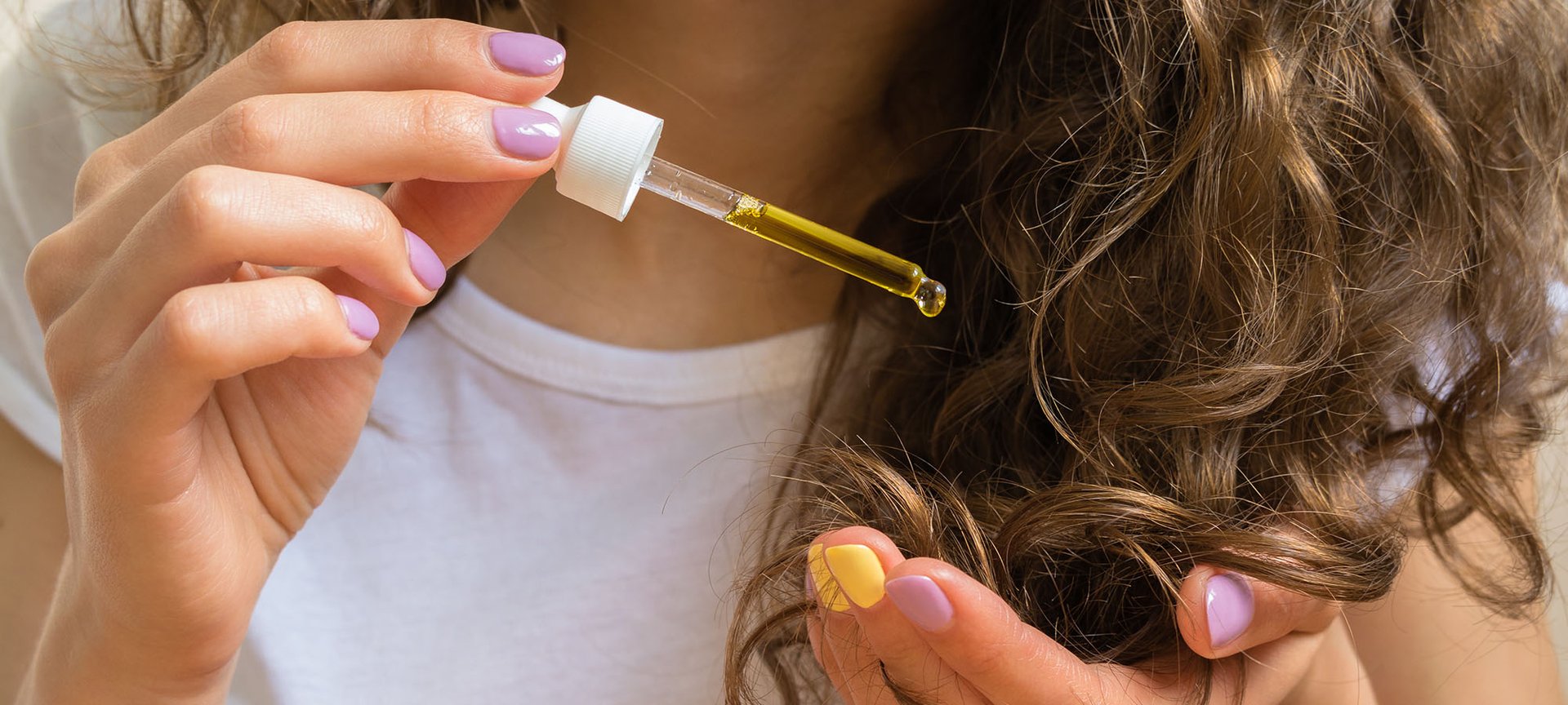 kobieta nakładająca olejek na końcówki kręconych włosów